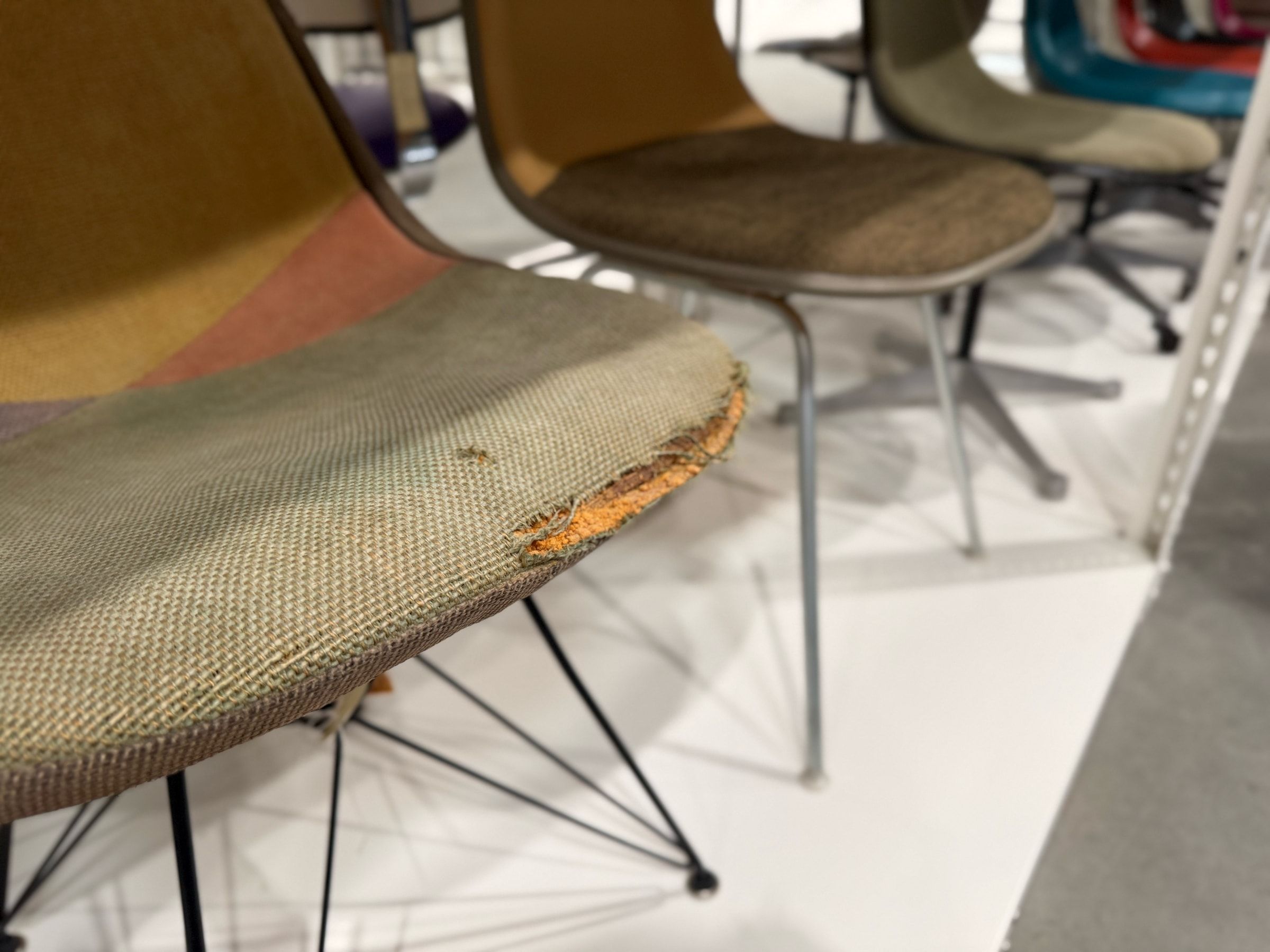 Close up photos of the front edges of a chair, fabric fraying from use.